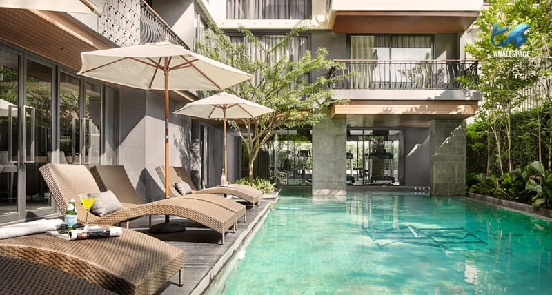 Inviting swimming pool with chaise lounges and umbrellas, with the gym visible in the background.
