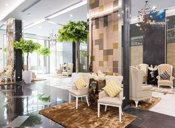 Elegant and spacious lobby with ornate seating, decorative trees, and sophisticated chandeliers.