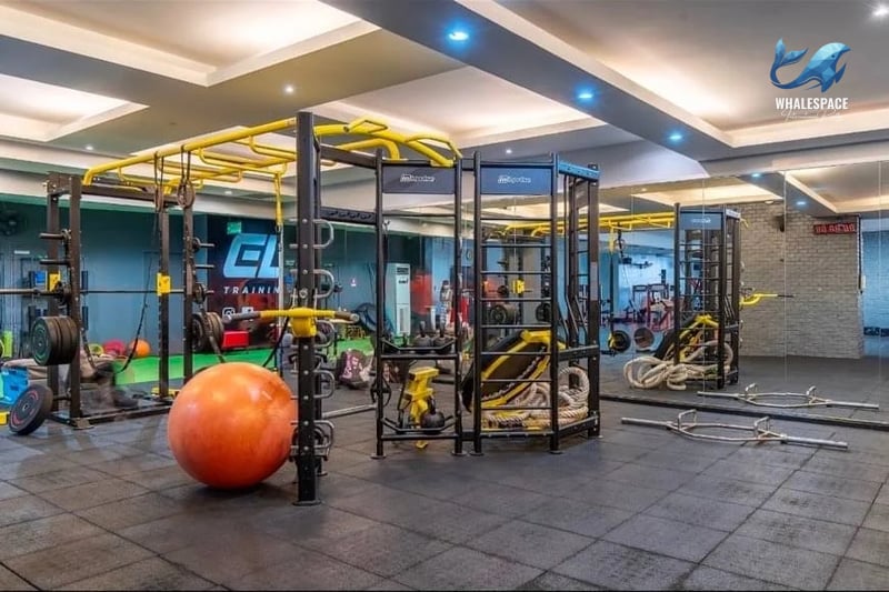 Spacious fitness center equipped with various weight training machines, free weights, and an orange exercise ball.