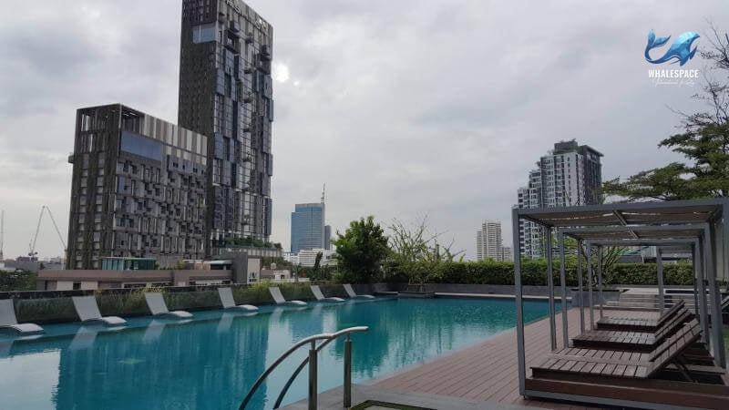 Expansive swimming pool surrounded by lounge seating with city buildings in the background