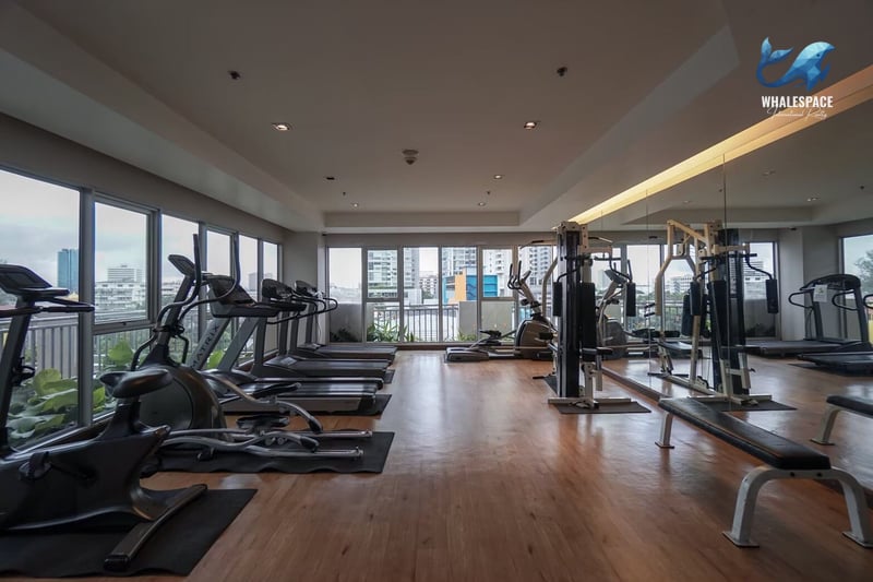 Well-lit fitness center with a range of cardio and weight machines, offering city views through large windows.