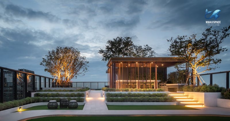 Beautifully landscaped rooftop garden with seating areas and a modern pavilion, illuminated at dusk.