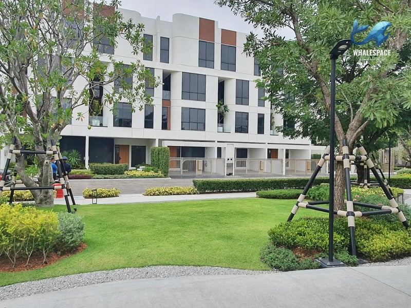 Modern townhouse facade with clean lines and large windows surrounded by greenery