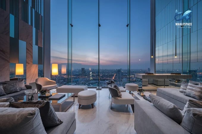 Luxurious lounge area with plush seating and floor-to-ceiling windows offering panoramic city views at dusk.