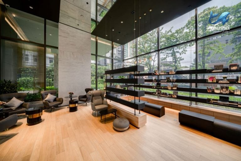 Spacious resident lounge with light wood flooring, stylish bookshelves, and comfortable seating arrangements