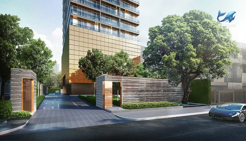 Modern building facade with golden accents and lush greenery surrounding the entrance.