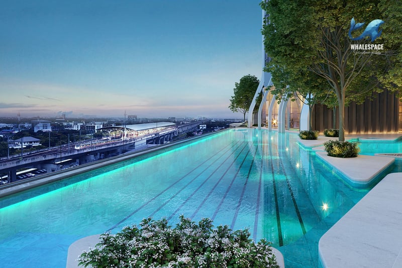 Outdoor infinity-edge swimming pool with a city and sky train view at dusk.