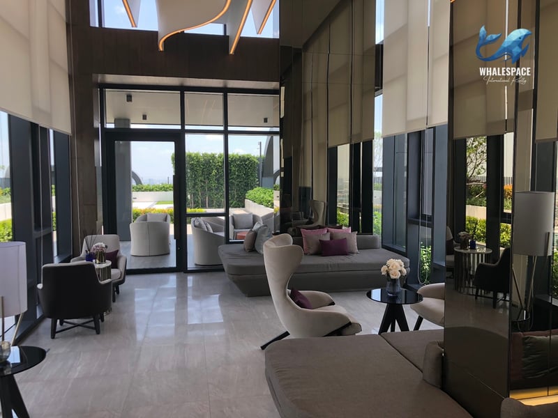 Elegant residents' lounge with polished marble flooring, stylish modern sofas and armchairs, mirrored wall panels, and large windows overlooking an outdoor terrace.