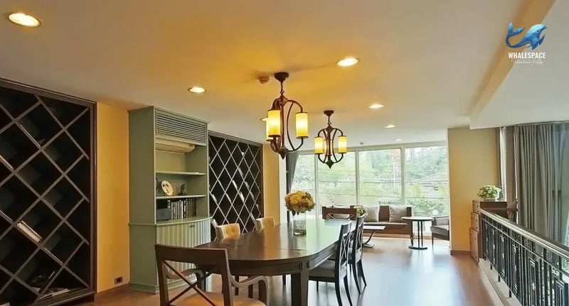 Spacious dining room featuring a large wooden table, elegant chandeliers, and a wine rack.