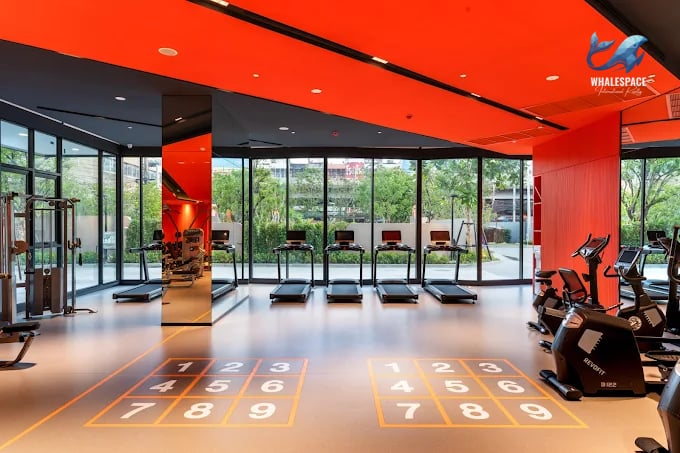 Vibrant and well-equipped fitness center featuring treadmills, ellipticals, and weight training machines, highlighted by an energetic orange ceiling.