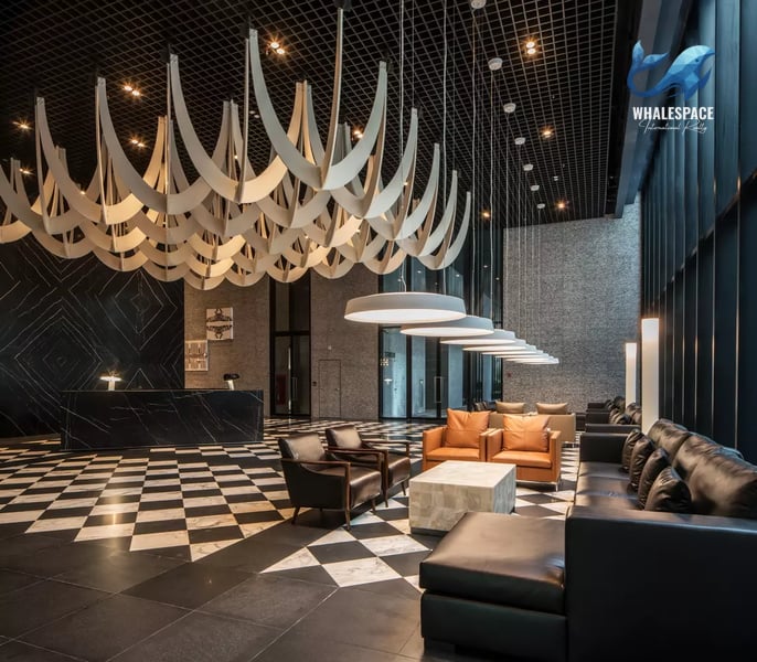 Grand hotel-style lobby with a striking abstract art installation, checkerboard marble flooring, and luxurious leather seating.