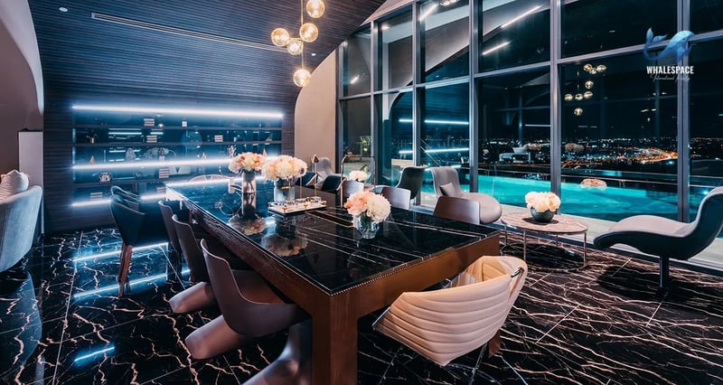 Luxurious dining area with a large marble table, modern chairs, and floor-to-ceiling windows offering city views.