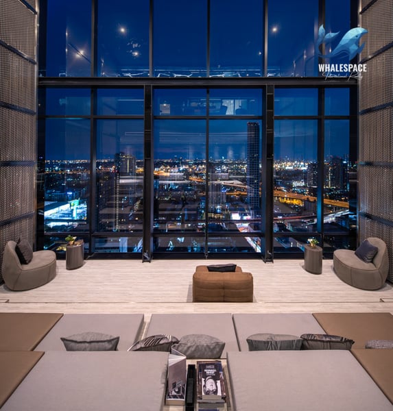 Luxurious lounge area with comfortable seating and floor-to-ceiling windows showcasing a stunning cityscape at night.