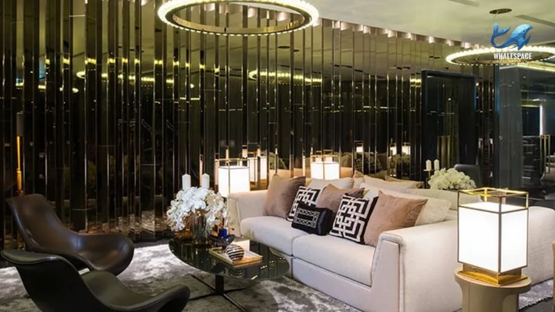 Luxurious lounge area with a plush white sofa, designer accent pillows, a mirrored coffee table, and unique circular chandeliers.