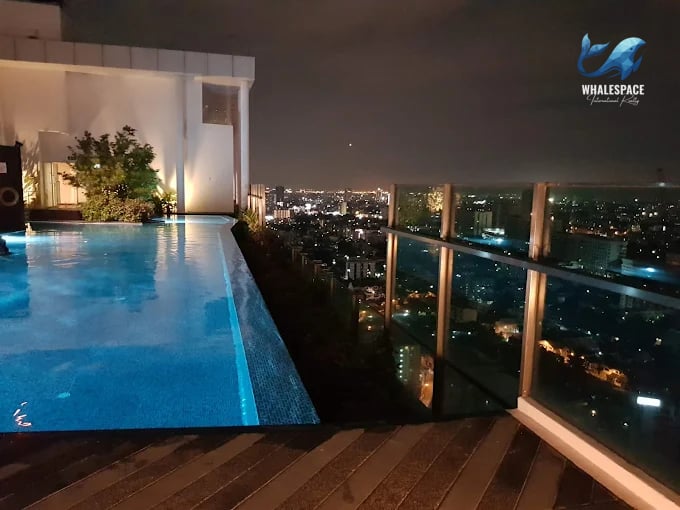 Illuminated rooftop infinity pool offering panoramic city views at night