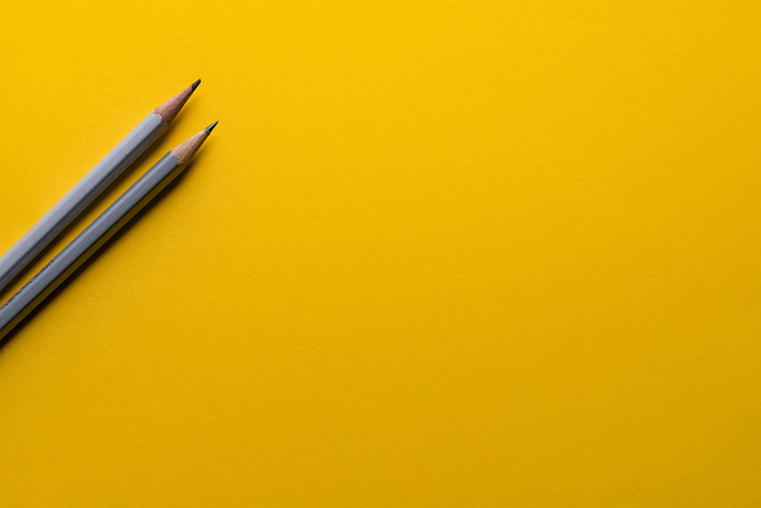 Two sharpened pencils on a bright yellow background