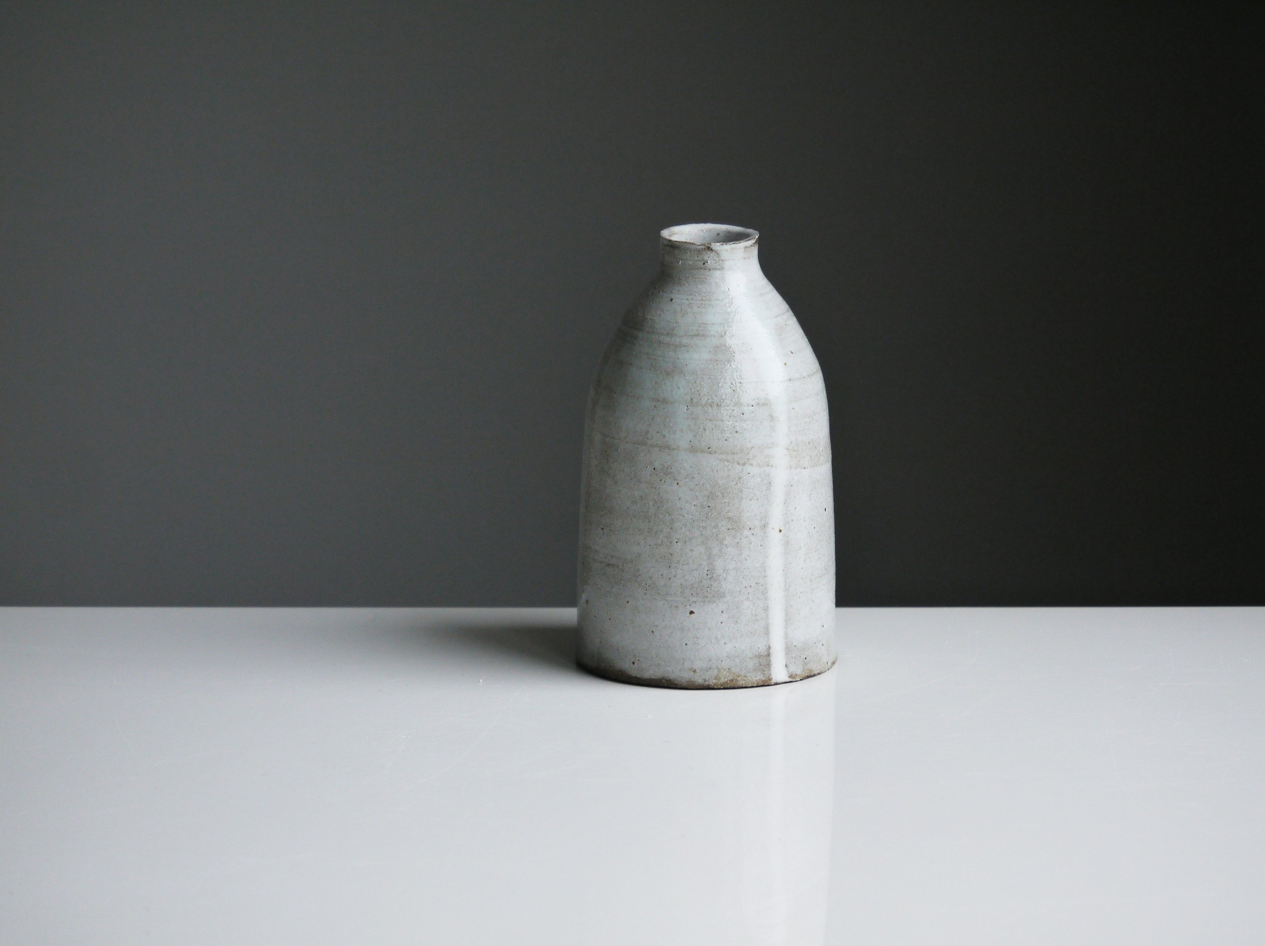 a piece of pottery on a light grey table, with a darker grey background behind.