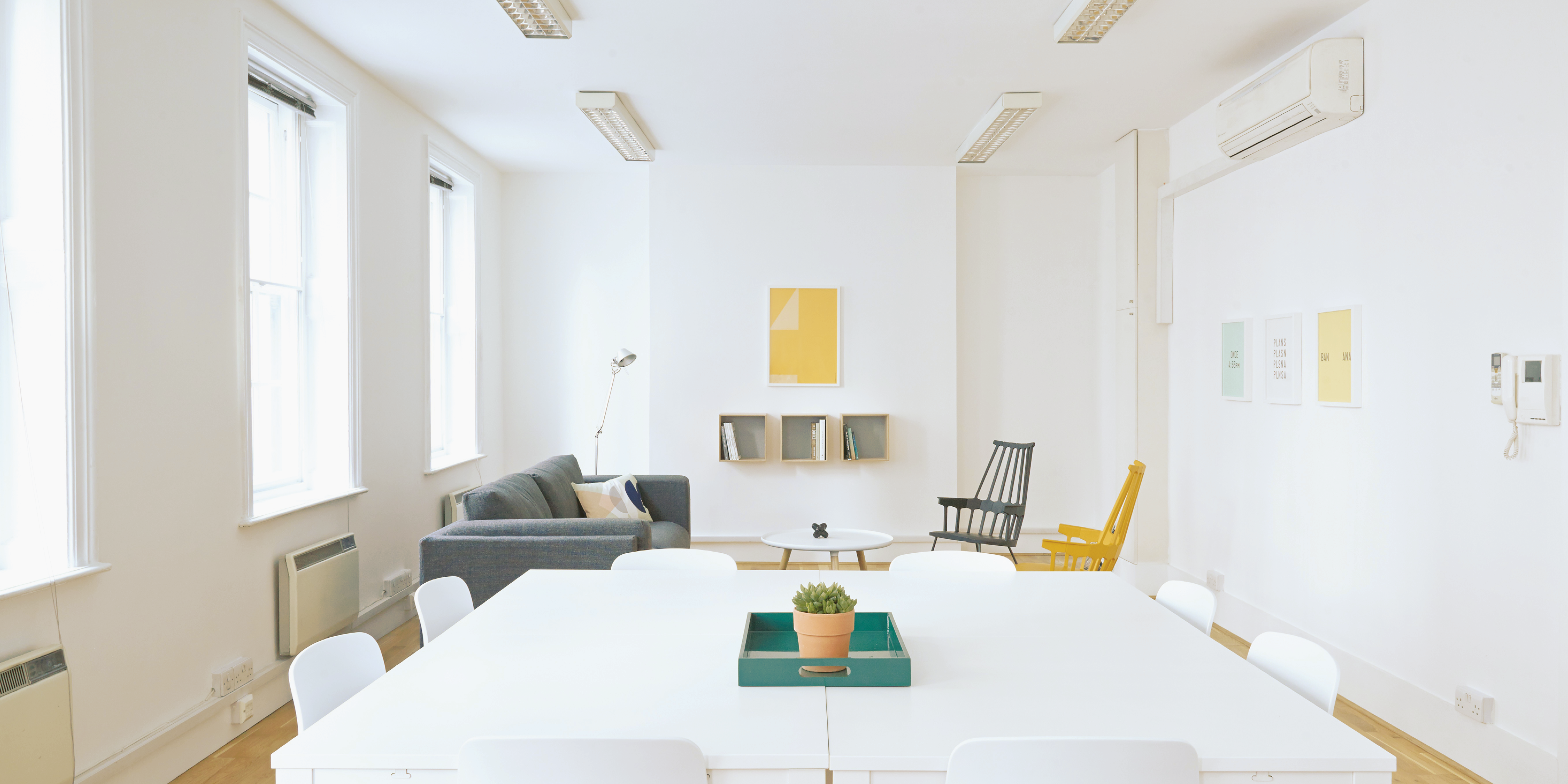 white room with bright windows, sofa and chairs, and square table with seating