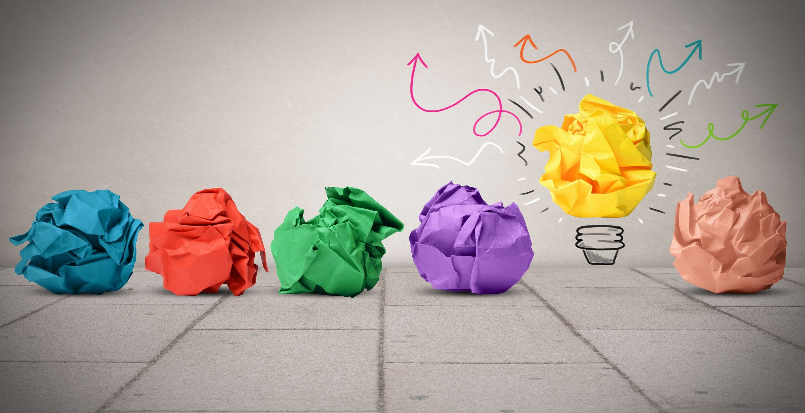 colourful crumpled balls of paper, with one surrounded by arrows to form a lightbulb illustration