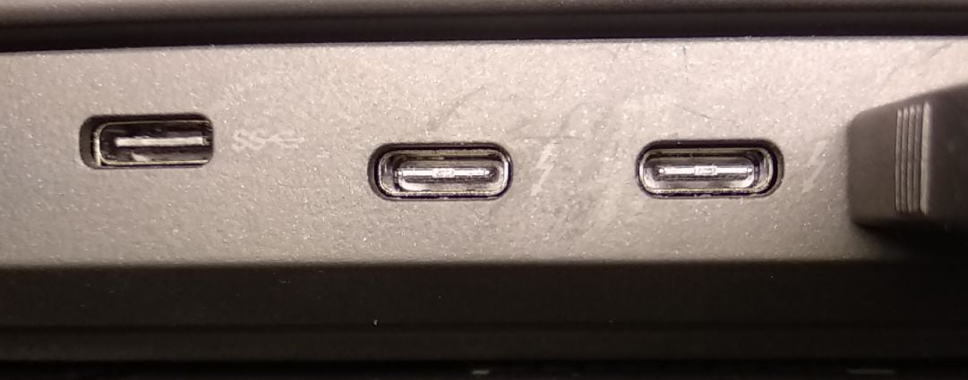 Detail tří USB-C portů notebooku, u prostředního je vidět symbol blesku.