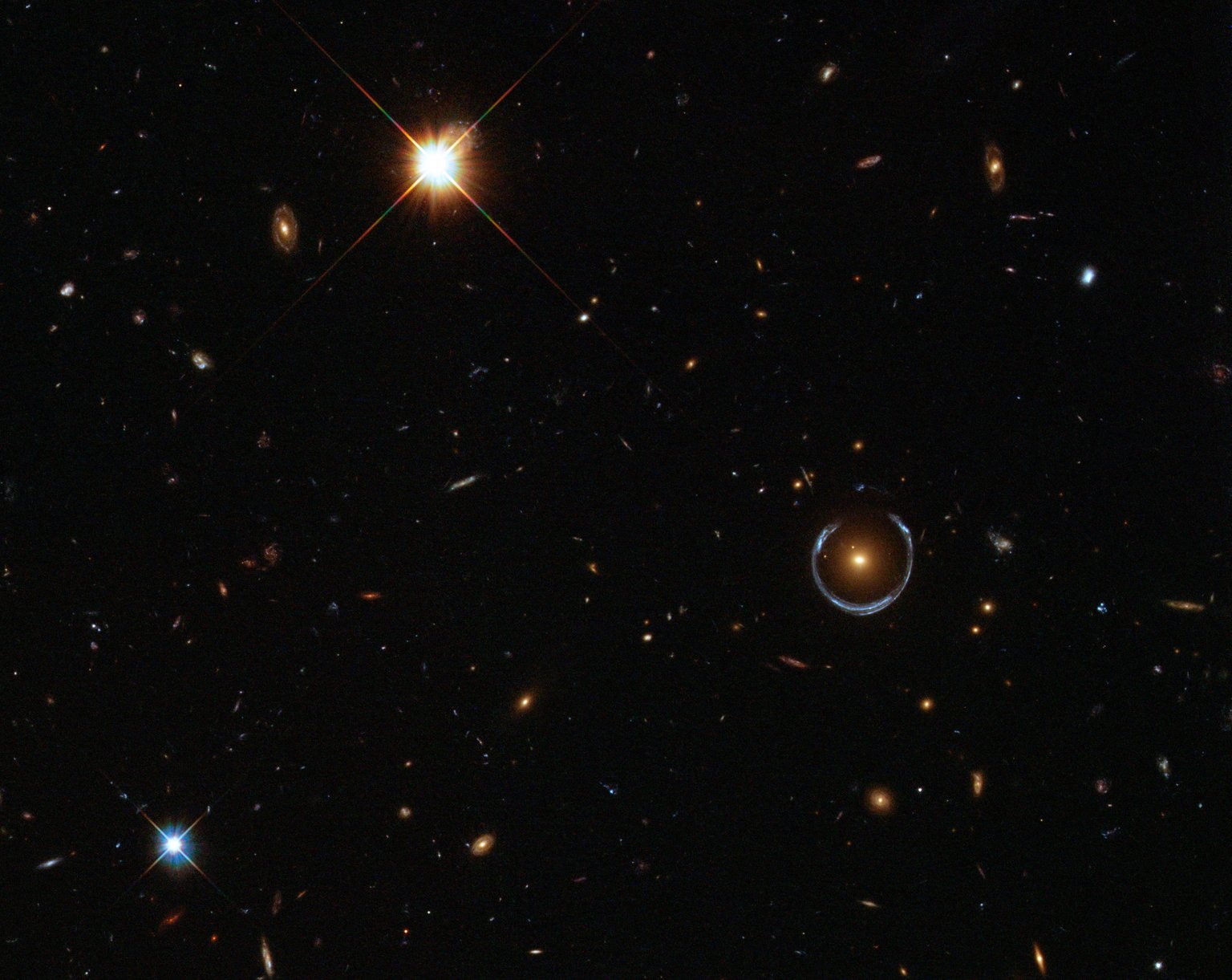 Oranžová galaxie obklopená modrým obloukem gravitační čočky Cosmic Horseshoe.