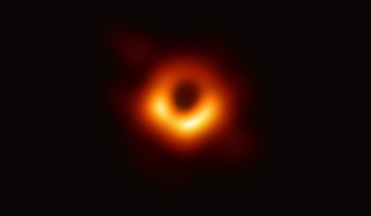 Skutečný rádiový snímek M87*: nerovnoměrně jasný oranžový prstenec obklopuje tmavý stín černé díry