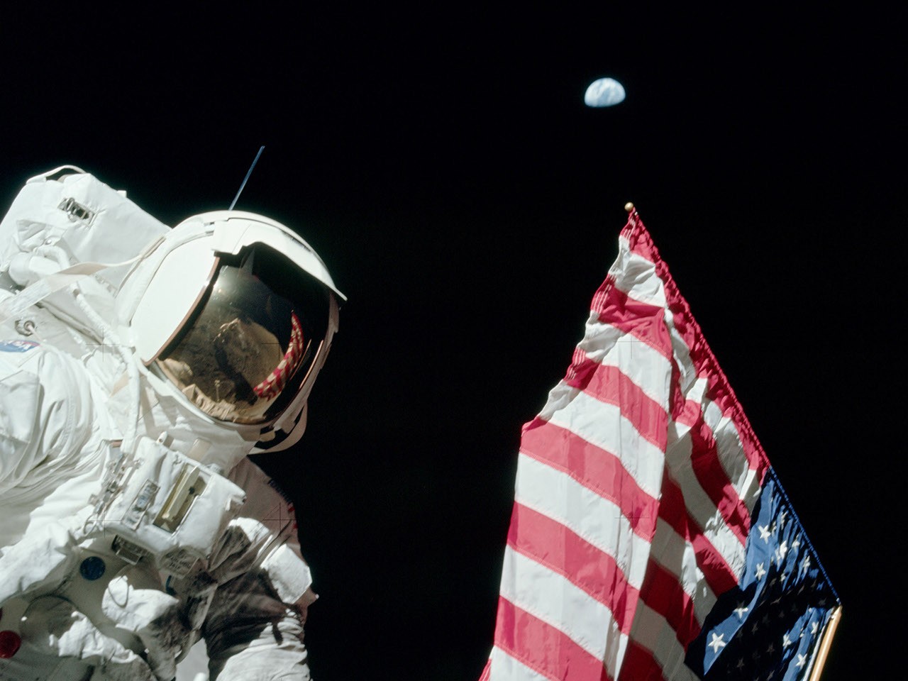 Harrison Schmitt u americké vlajky na Měsíci, nad ním je vidět Země.
