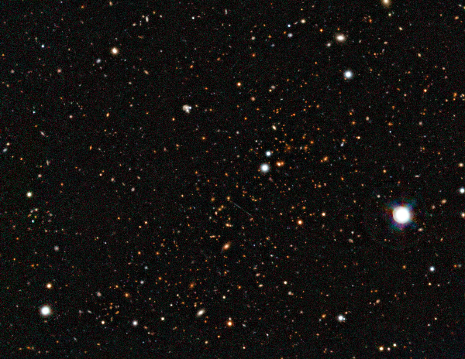Snímek kupy galaxií El Gordo, podlouhlý shluk slabých galaxií v hvězdném poli