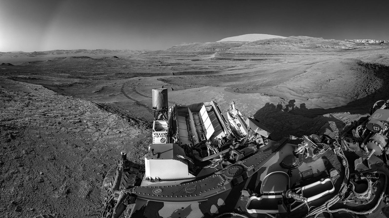 Záď Curiosity s generátorem MMRTG a stopami kol v marsovském terénu