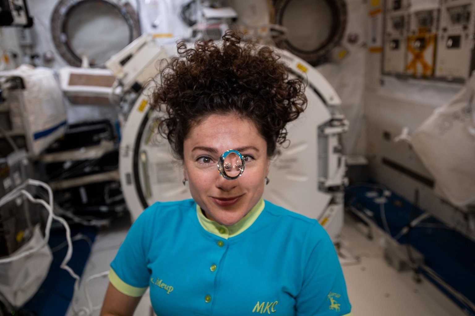 Jessica Meir pozoruje volnou kapku vody před obličejem v modulu Kibó na ISS.