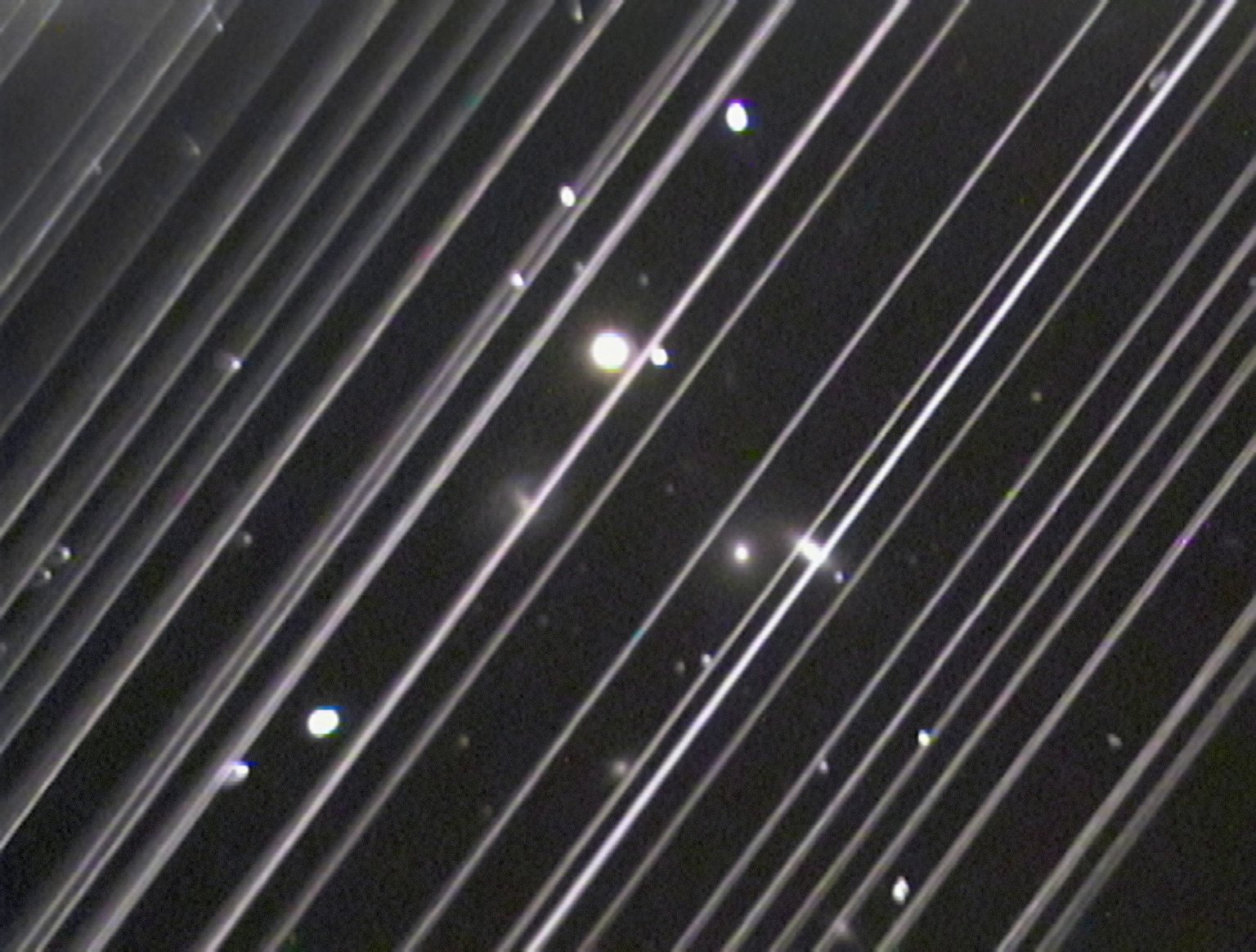 Šikmé stopy Starlinků překrývají astronomický snímek skupiny galaxií NGC 5353/4