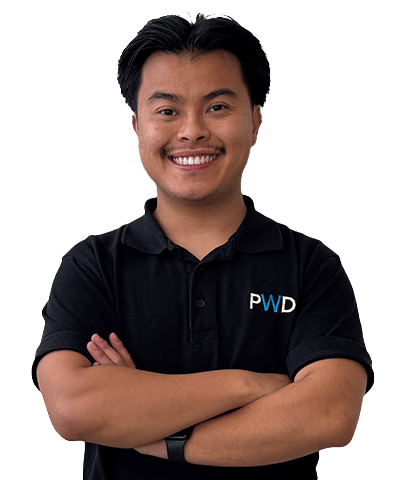 A smiling person with short dark hair, wearing a black polo shirt with the letters PWD on it, stands with arms folded against a plain white background. This is Allan Truong.