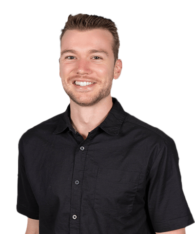 John Weckman, a smiling man with short light brown hair and a trimmed beard, wears a black short-sleeve button-up shirt as he stands against a plain light background.