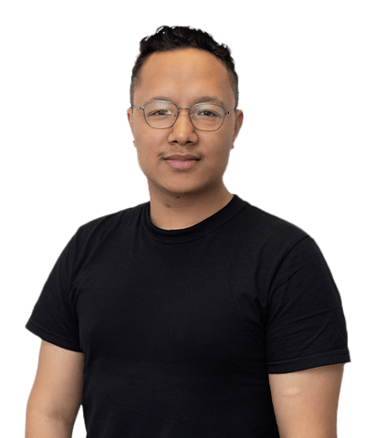 Rabsun Shrestha, with short, curly hair and glasses, is wearing a black T-shirt and standing against a plain white background, looking directly at the camera with a neutral expression.