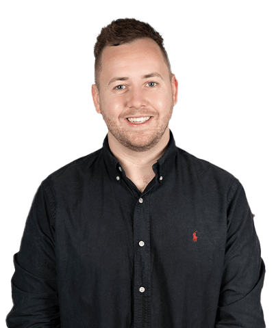 Scott Donovan, a smiling man with short brown hair and a trimmed beard, wears a black button-up shirt with a small red logo, standing against a plain light background.