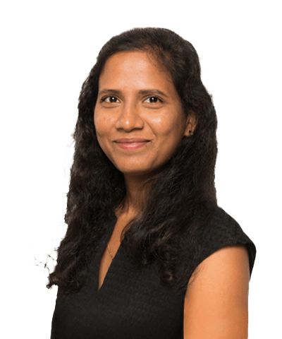 Nymisha Joginpally, with long, wavy dark hair and a medium skin tone, smiles at the camera. She is wearing a black sleeveless top and is posed against a plain white background.