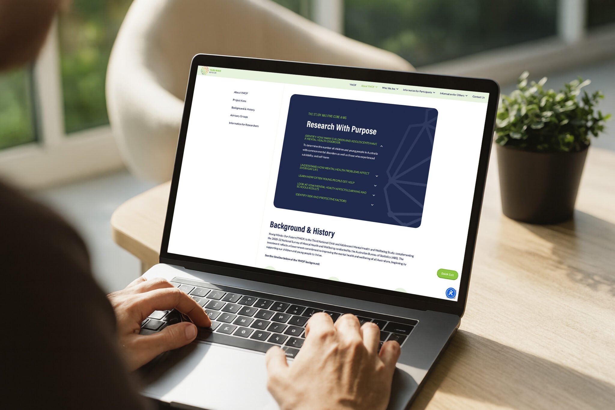 A person types on a laptop displaying a webpage titled Research With Purpose, inspiring young minds. The screen shows text, bullet points, and a section labelled Background & History. A potted plant and window are in the background, hinting at a bright future.