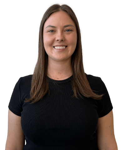 A woman with straight brown hair, wearing a black short-sleeve shirt, smiles whilst standing against a plain white background.