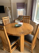 Solid oak dining table with 4 brown leather upholstered chairs.