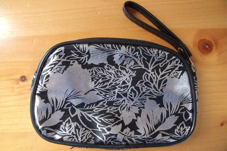 	Unused silver metallic/black leaf design coin purse with wrist strap. Happy to post.