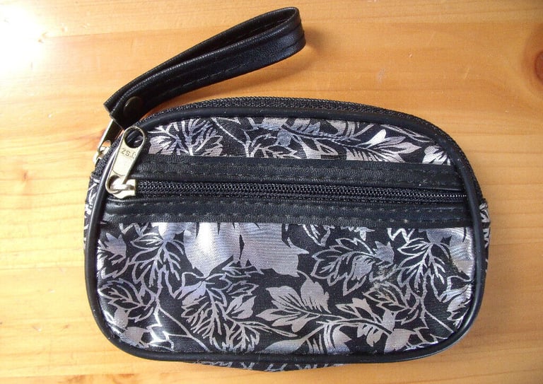 	Unused silver metallic/black leaf design coin purse with wrist strap. Happy to post.