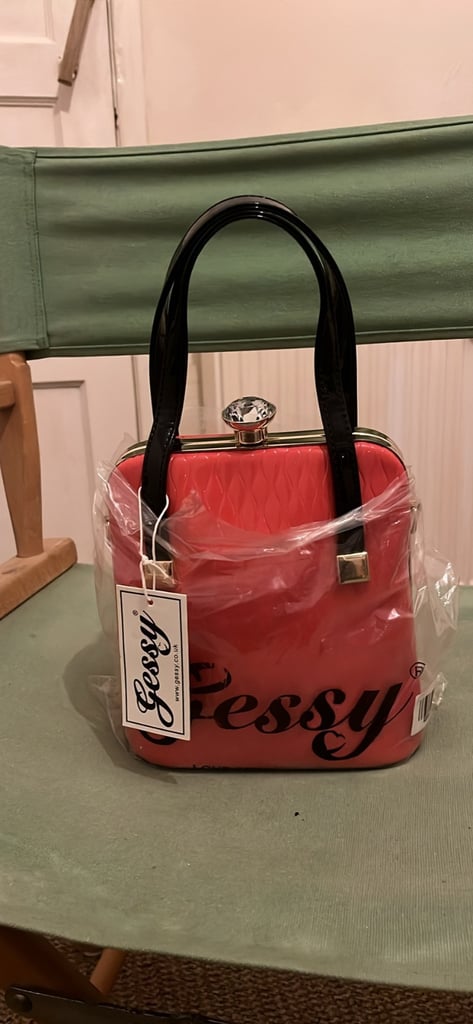 the handbag is a red, box-shaped handbag by the brand Gessy