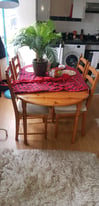Solid pine extendable dining table with four upholstered chairs.