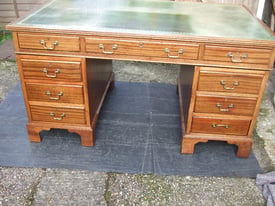 A large vintage/antique desk with nine drawers and leather top