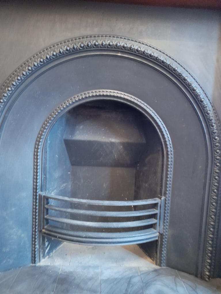 Cast iron fireplace insert with solid wood mantelpiece and black tiled hearth