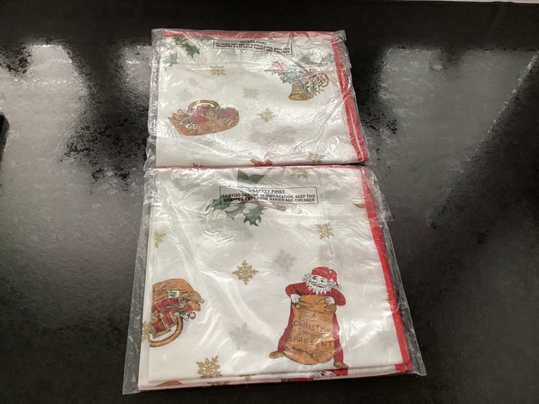 Two new sealed packs of fabric Christmas napkins. Four in each pack