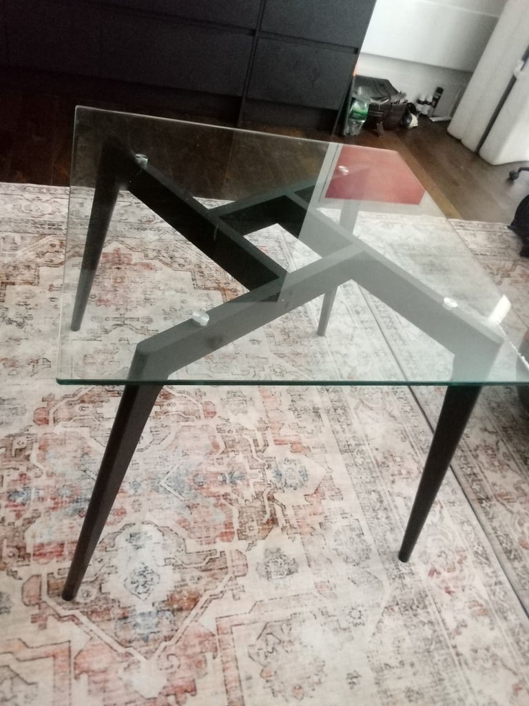 Glass dining table with two black wooden chairs