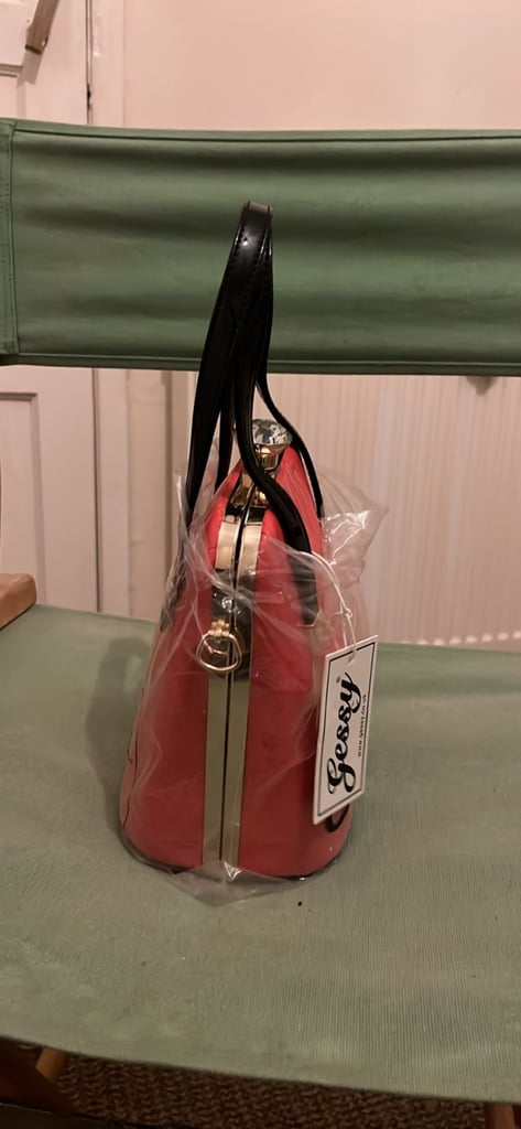 the handbag is a red, box-shaped handbag by the brand Gessy