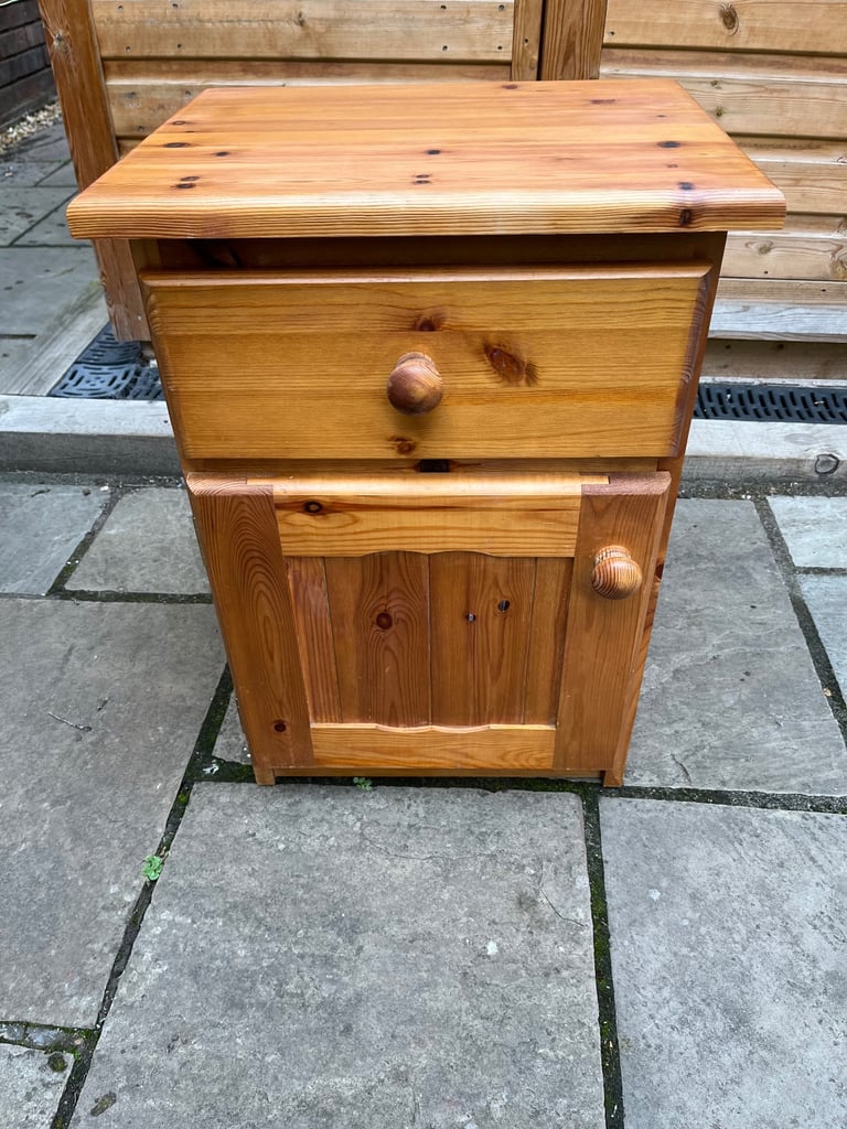A knotted pine bedside cabinet with drawer and cupboard.