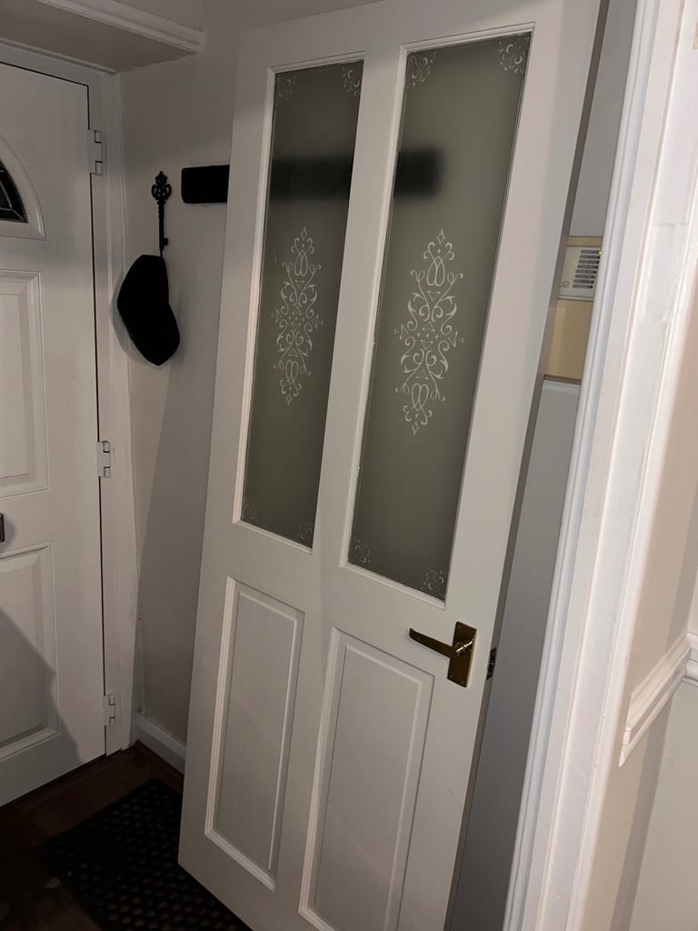 Interior door with frosted, ornate panels.